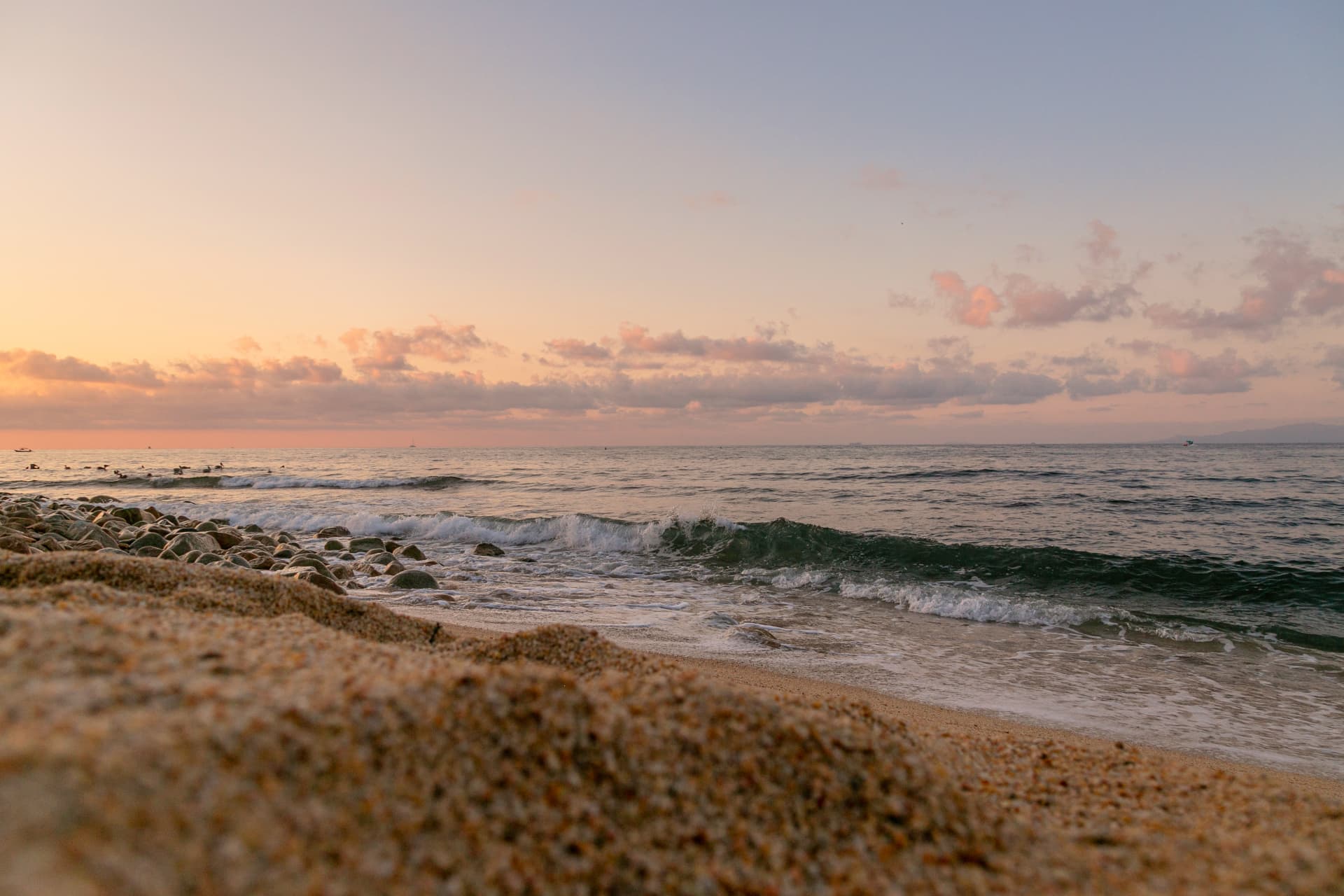 Waves breaking over the stones at sunrise with a pink sky in Quimixto