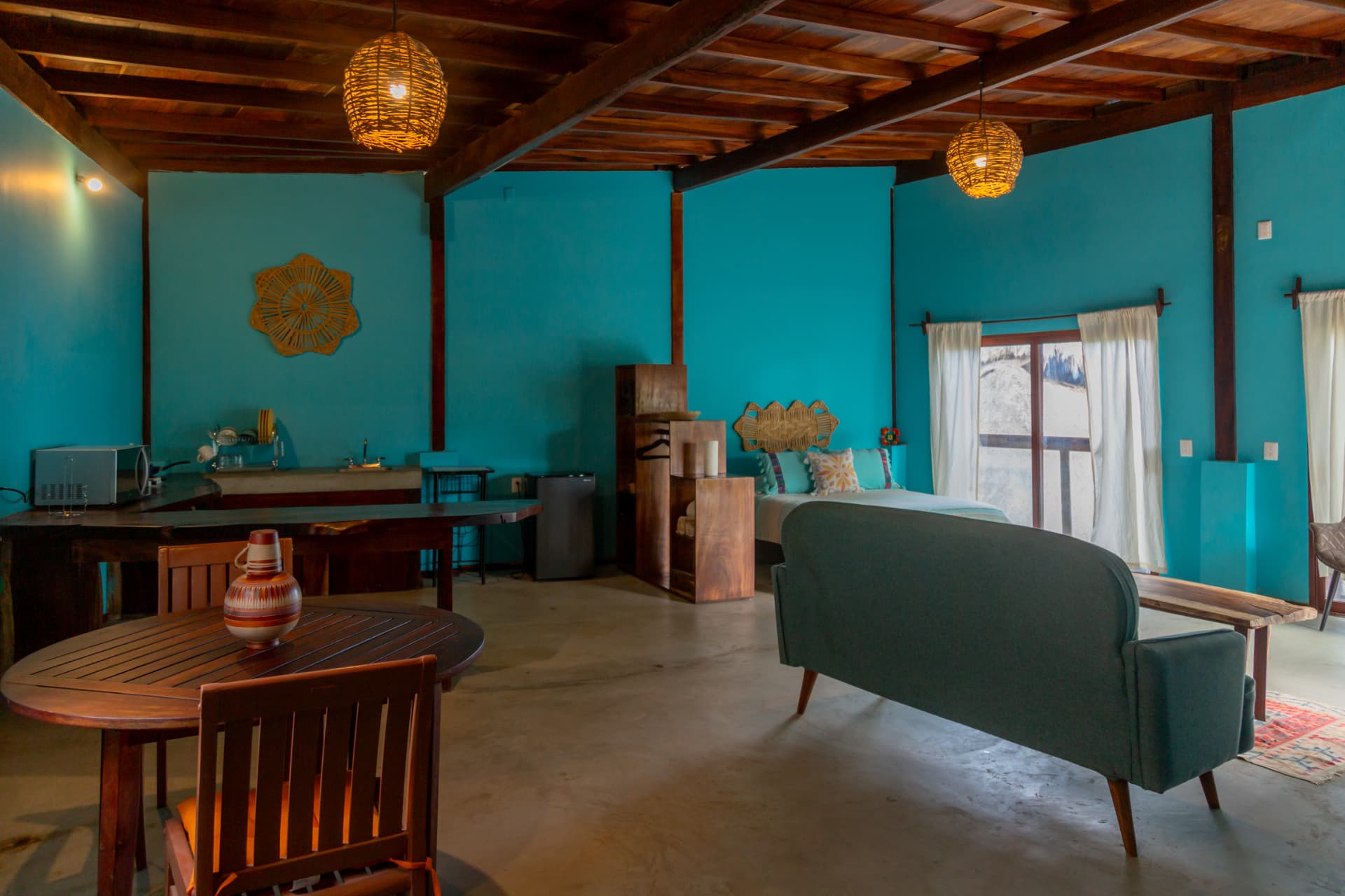 Montaña: comedor de madera, cocineta y cama junto al ventanal con vista al jardín