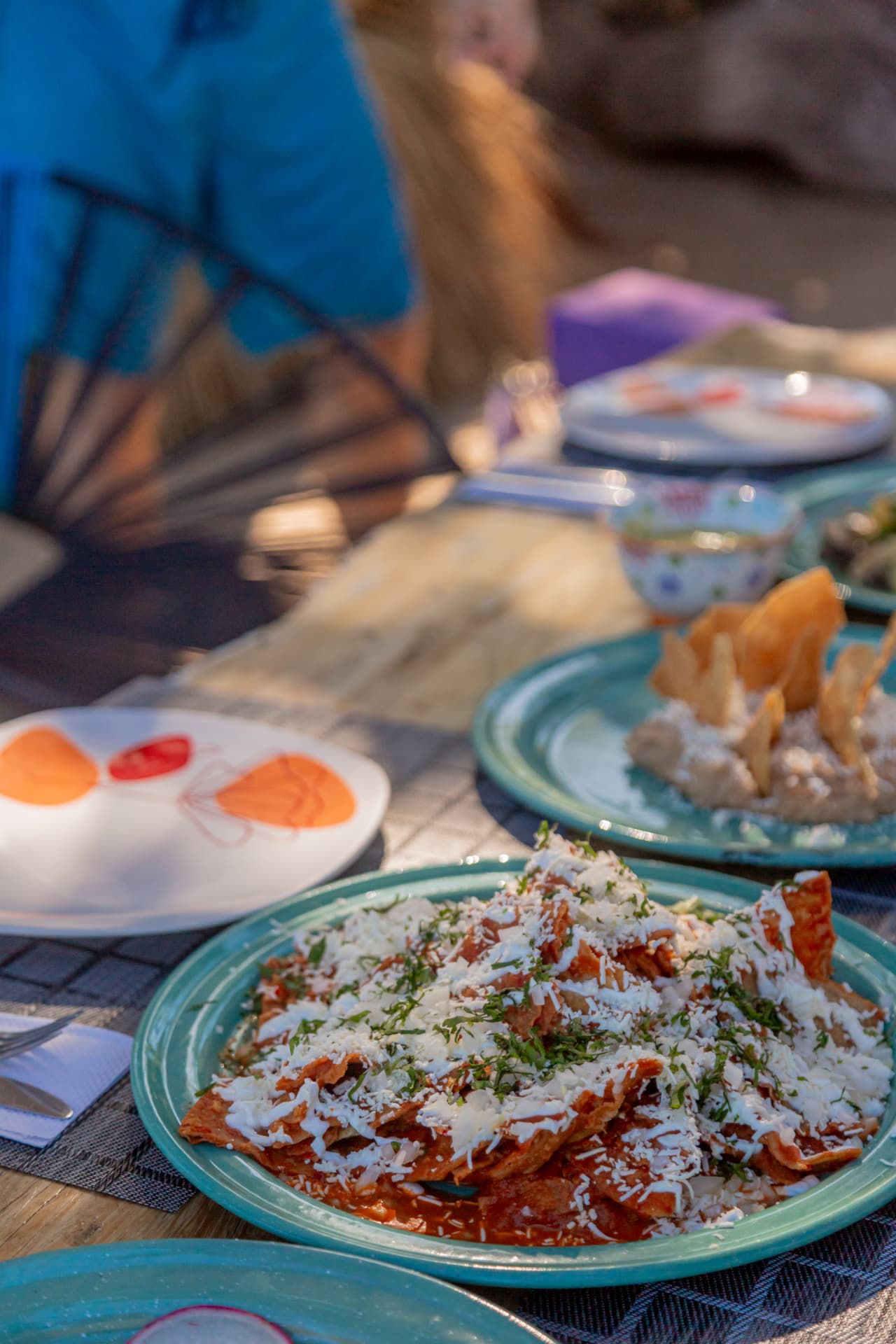 Chilaquiles rojos con queso y crema servidos en plato turquesa