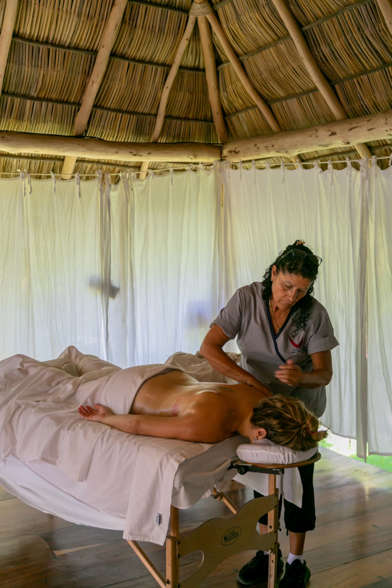 Therapist working in the spa palapa with white curtains