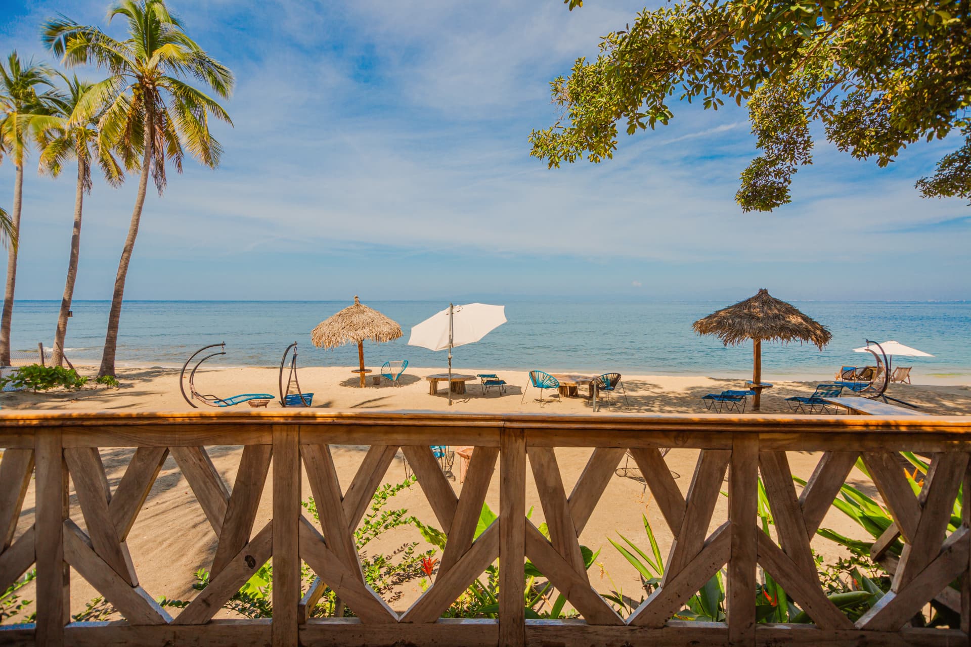 View of the beach and palm umbrellas from the hotel's wooden deck
