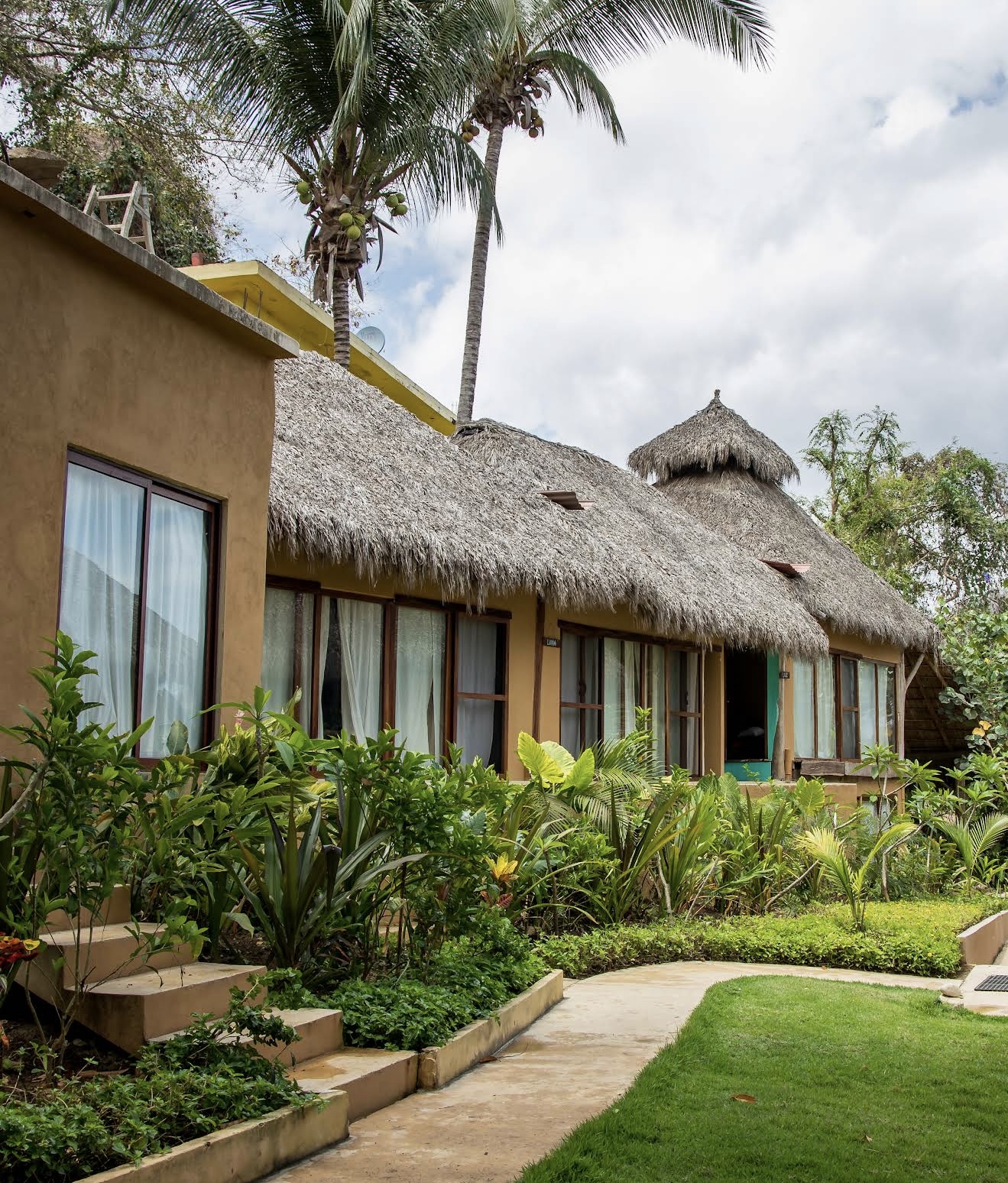 Exterior de la habitación familiar con techo de palapa y jardín tropical