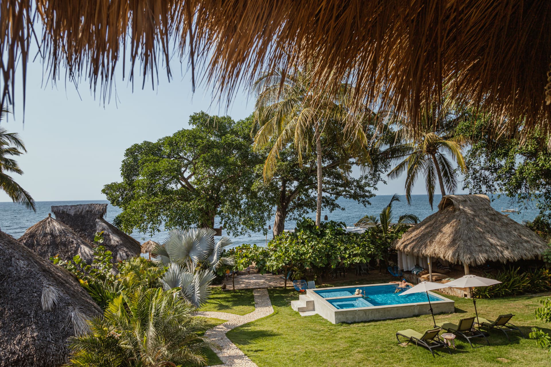 The pool at Amaca Beach Retreat surrounded by palm trees
