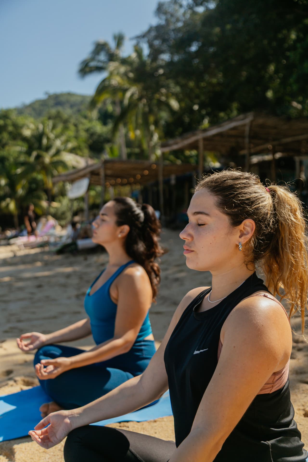 Close-up of two women meditating with their eyes closed on the beach