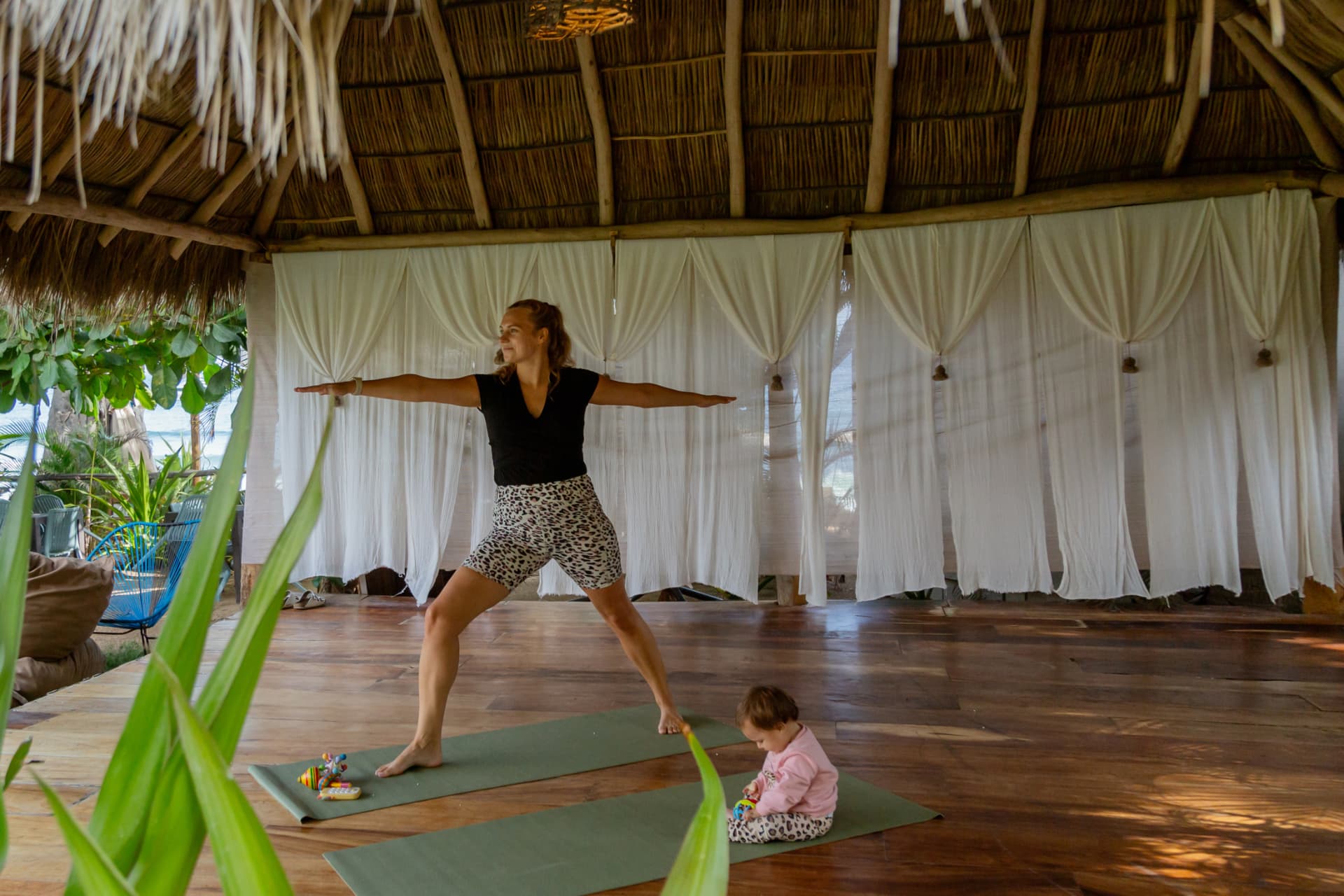 Warrior pose on the yoga deck with cotton curtains