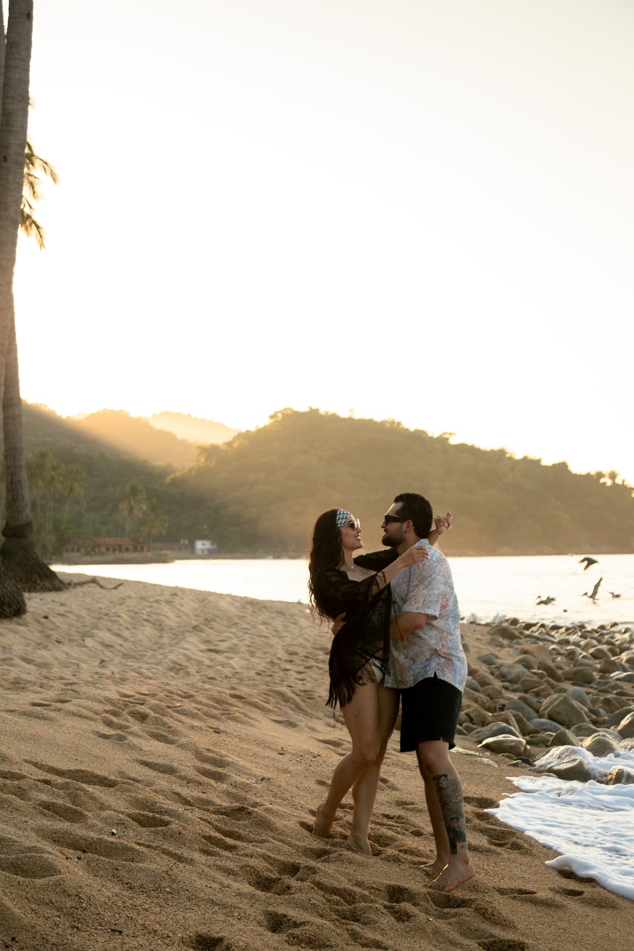 Couple dancing on the sand by the sea with the golden hills behind