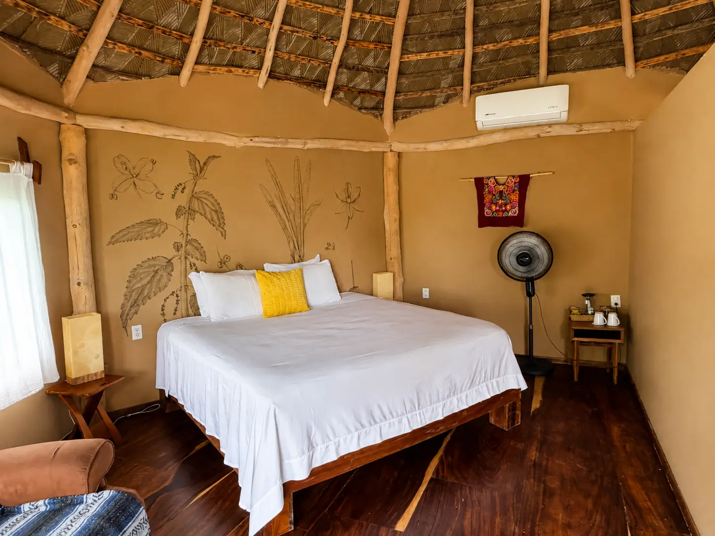 Cama King bajo el techo de palapa con murales pintados a mano