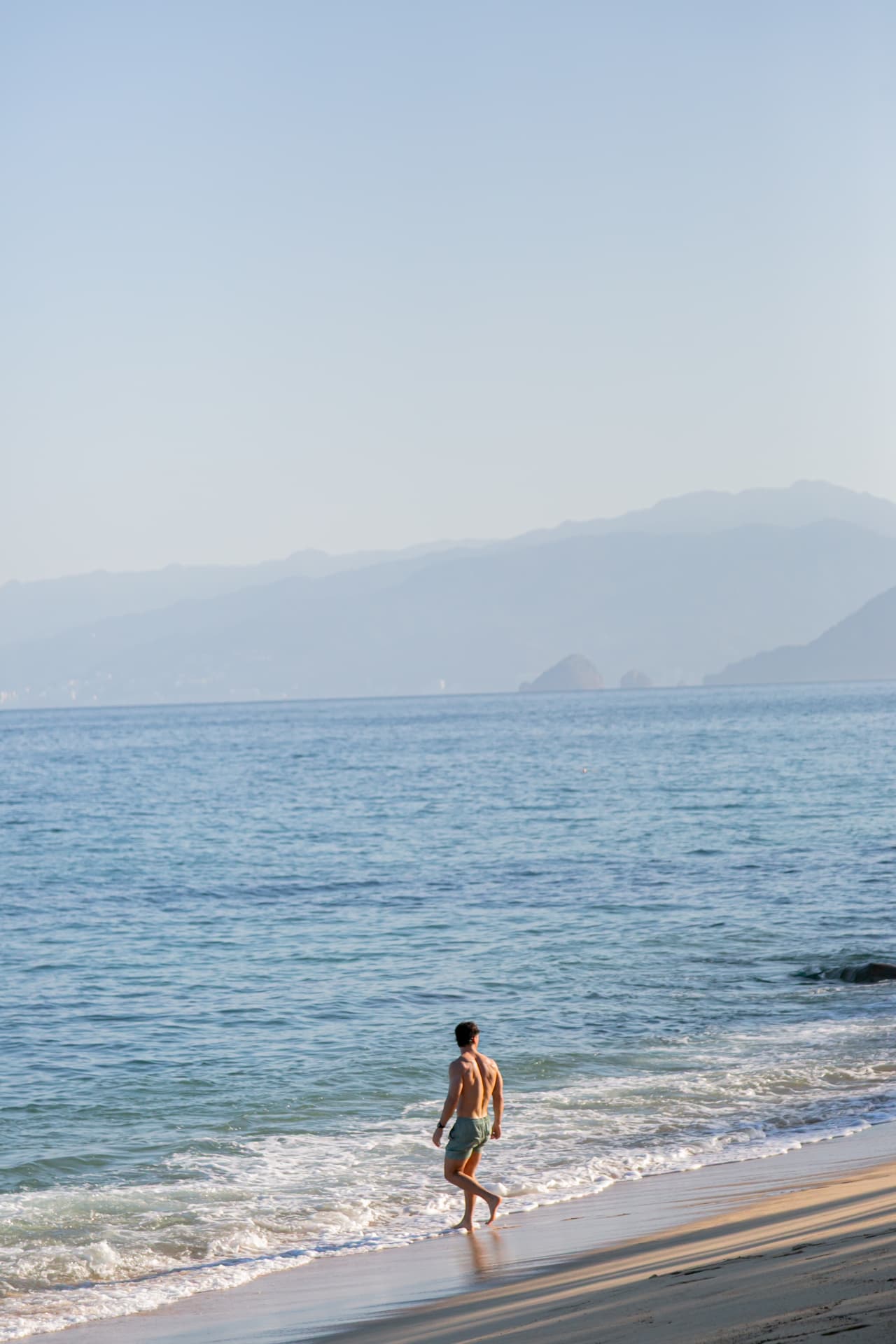 Man walking alone along the shoreline on a quiet morning
