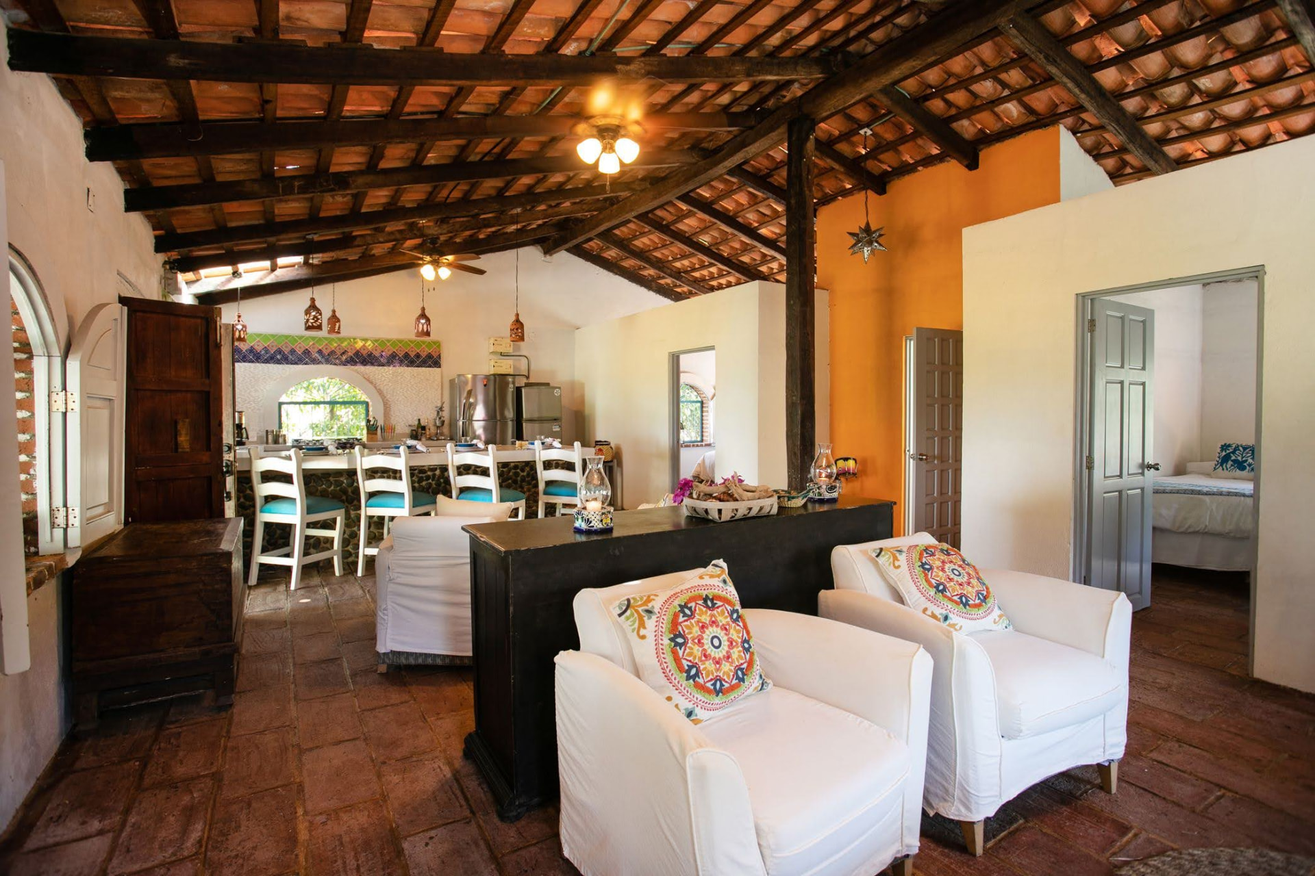 Villa: cocina completa, barra con bancos y sala con sillones blancos