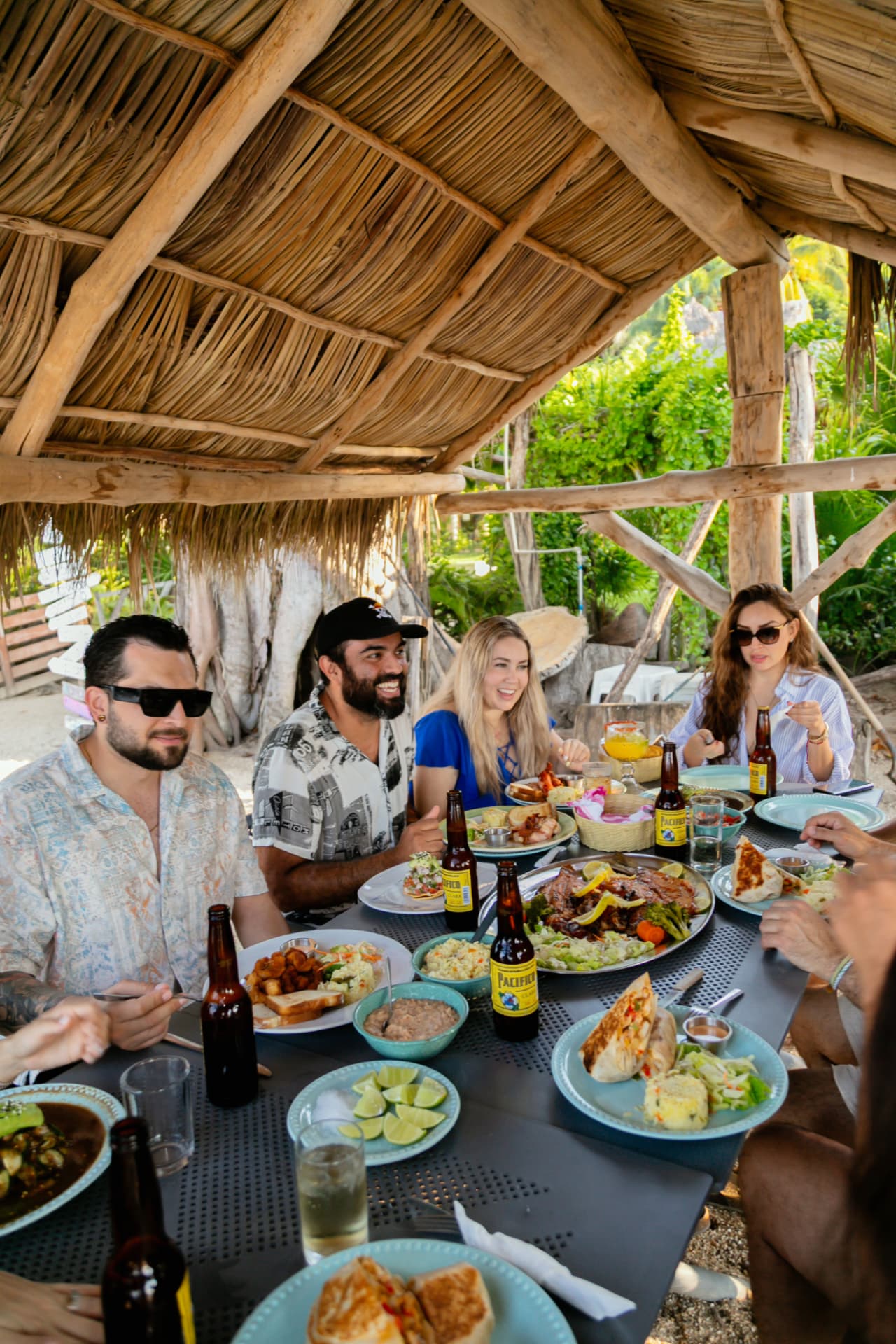 Friends sharing a long table with food at the beach club