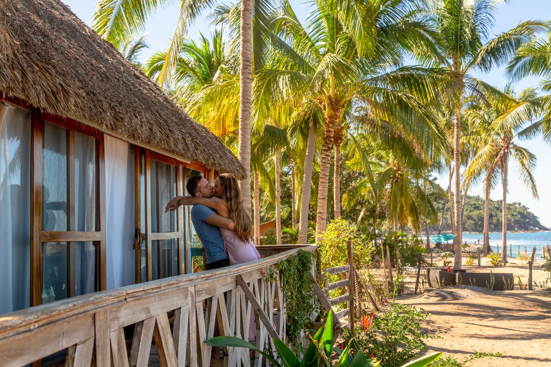 Pareja en el balcón de la suite frente a las palmeras y el mar