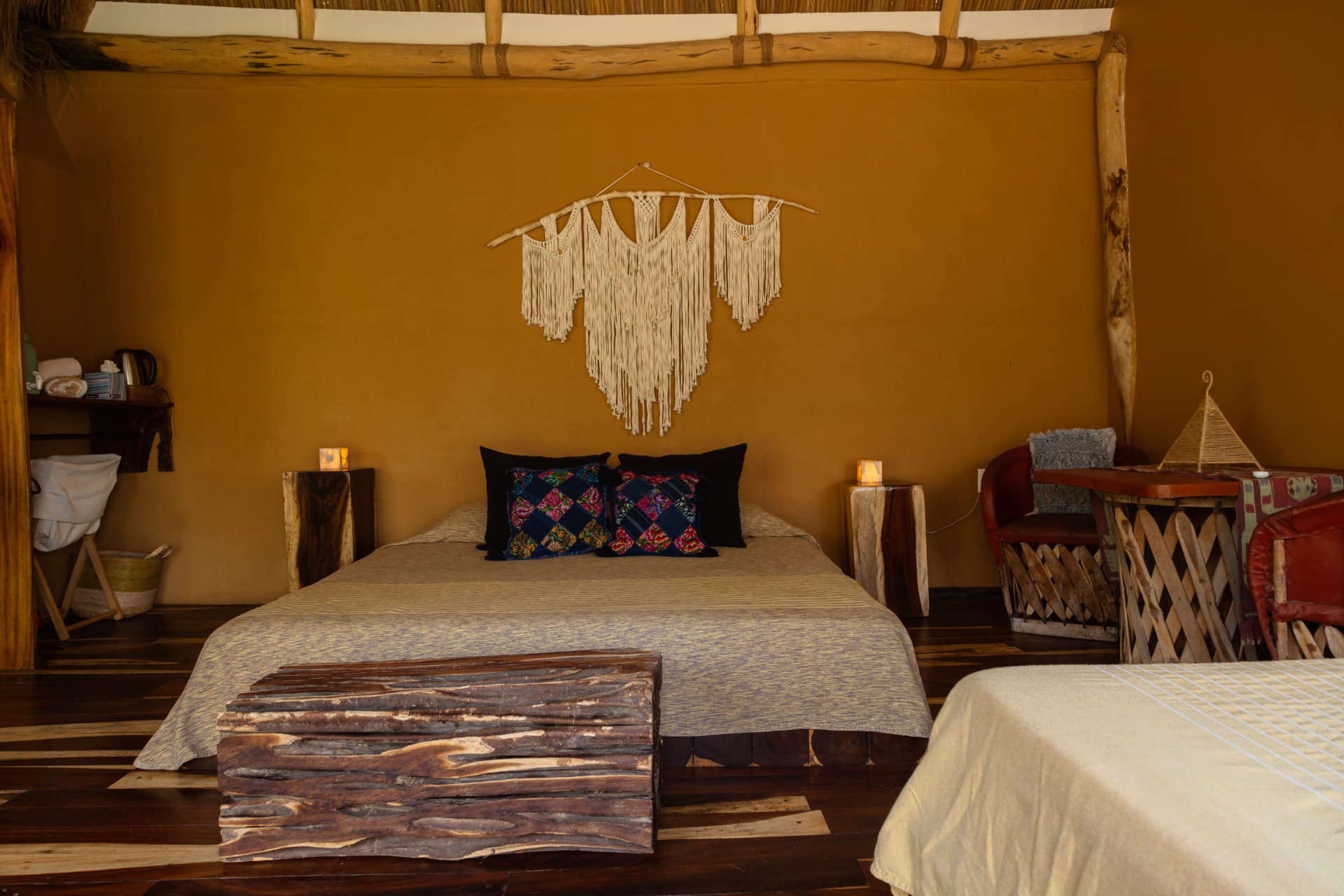 Luz: vista frontal de la cama King con banca de tronco y burós de madera