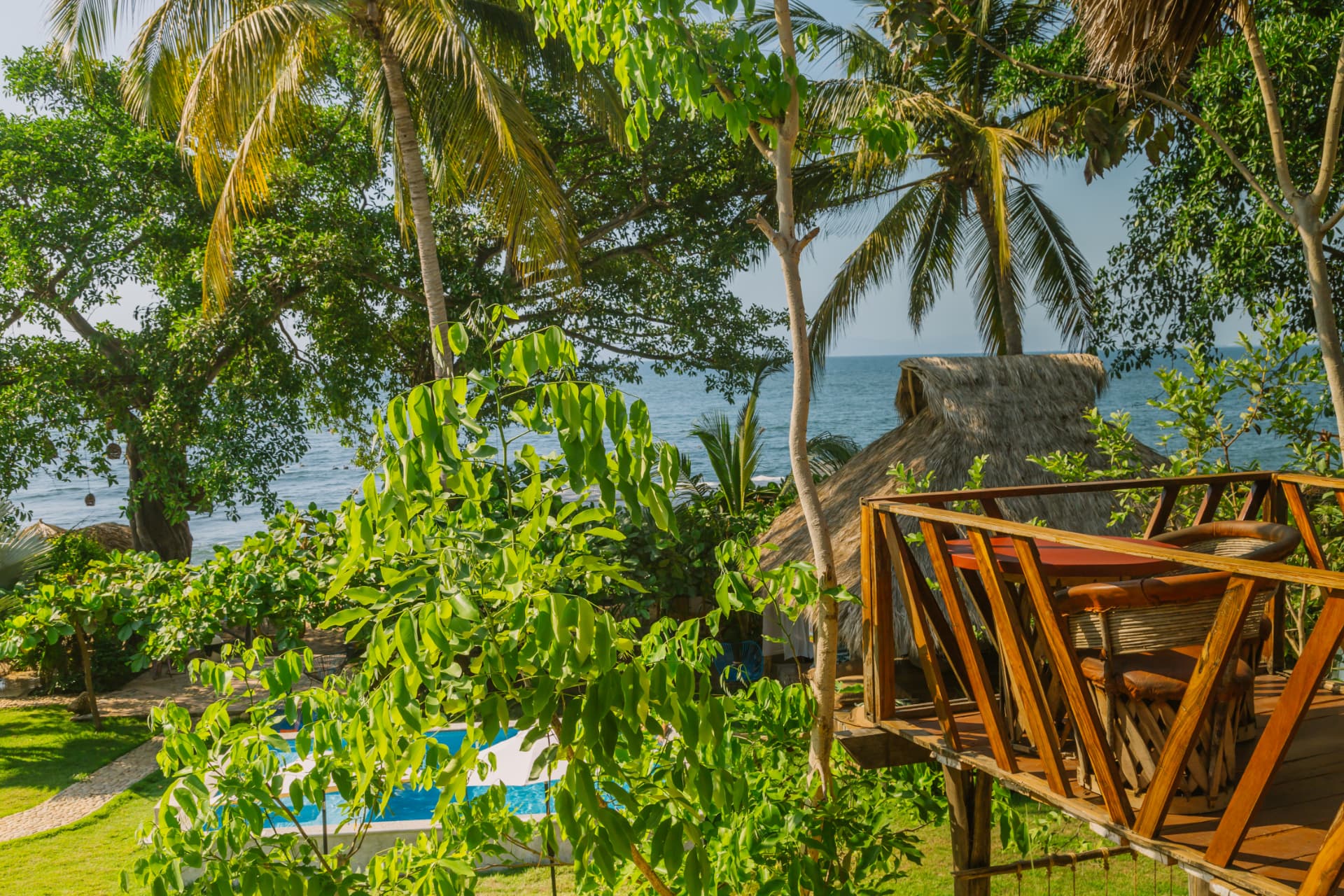 View of the pool from the terrace among palms with the sea behind