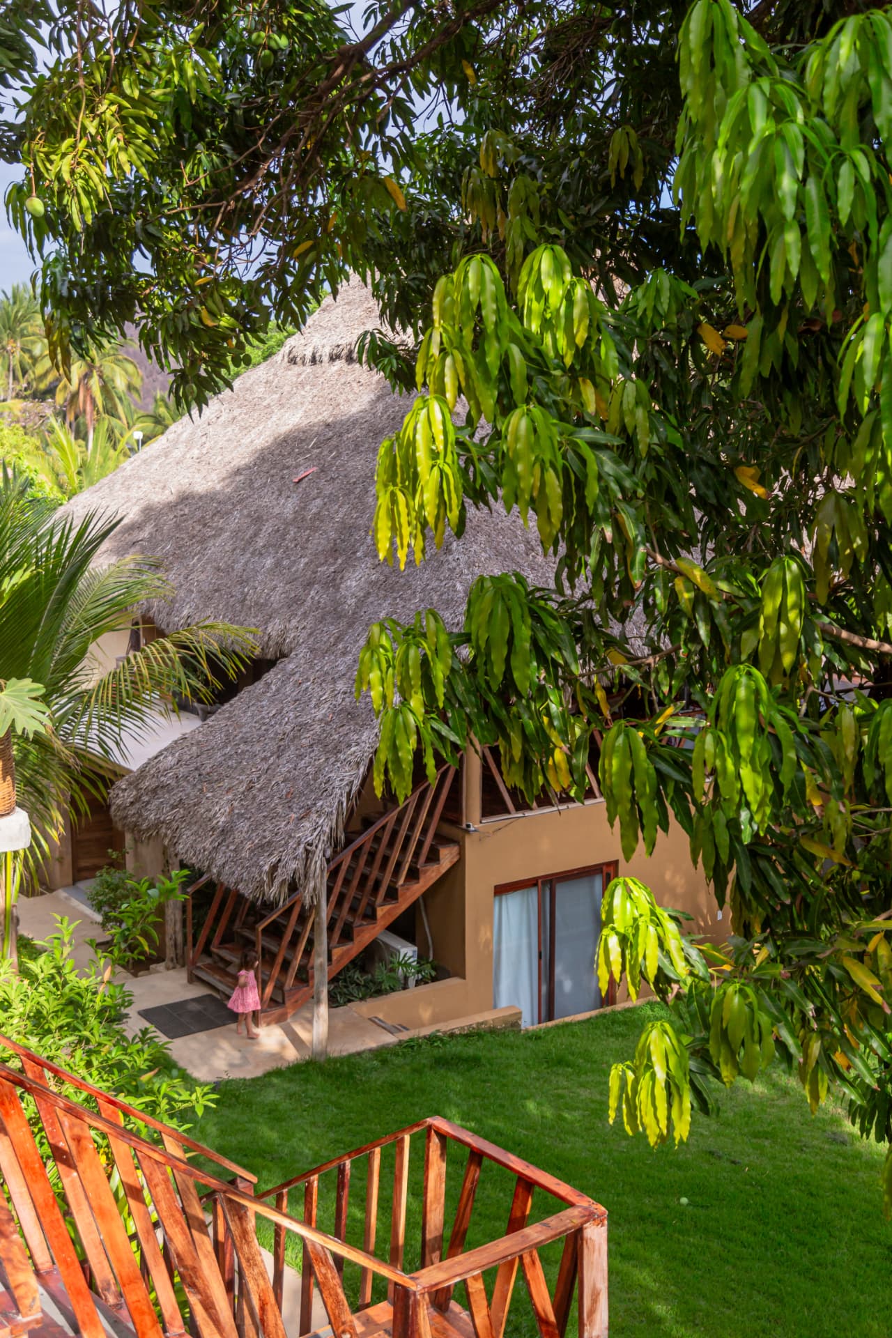 Nube: exterior con techo de palapa, escalera de madera y jardín tropical