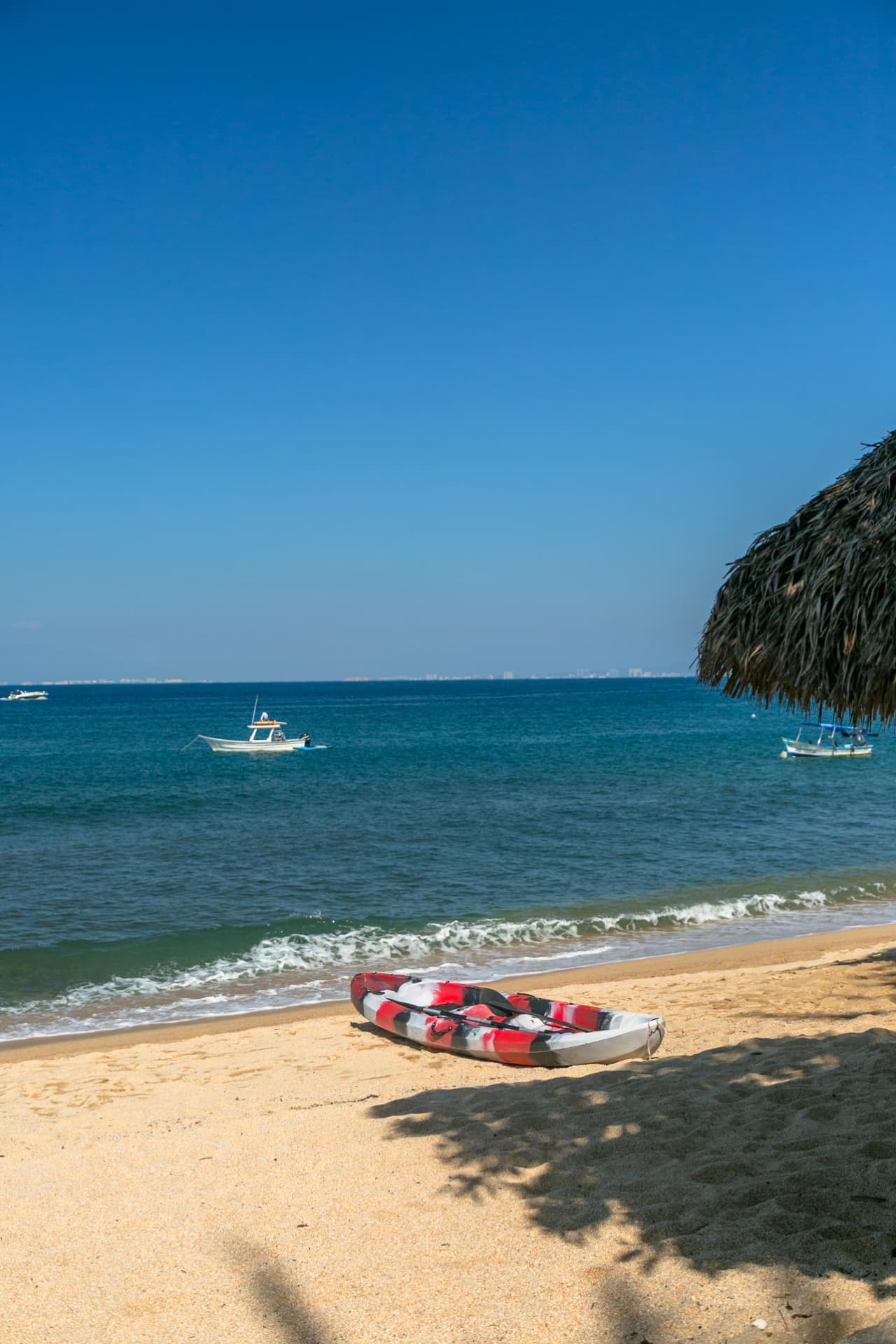 Kayak on the shore of Quimixto beach with boats and Banderas Bay behind
