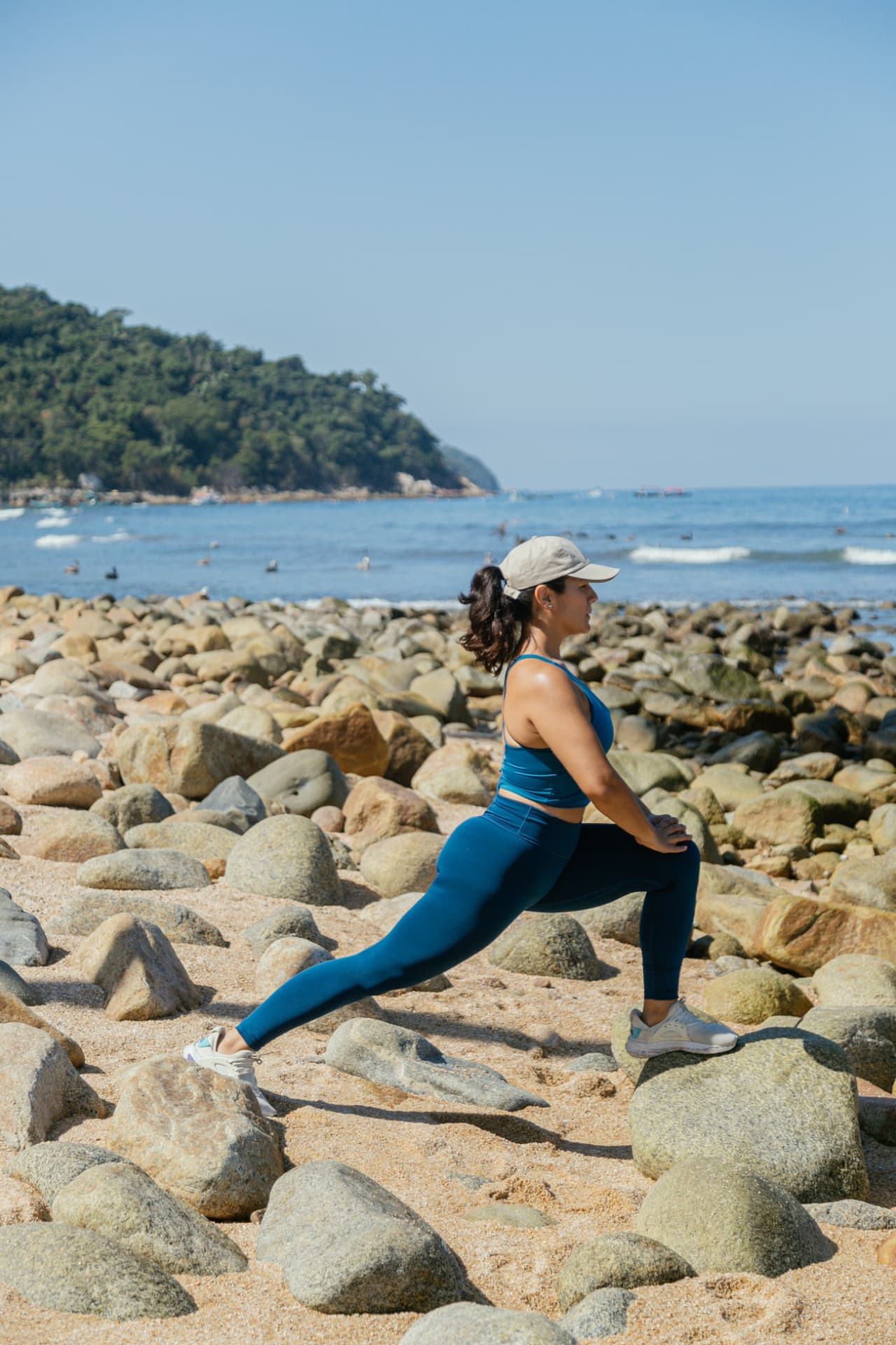 Woman stretching among the beach stones facing the bay