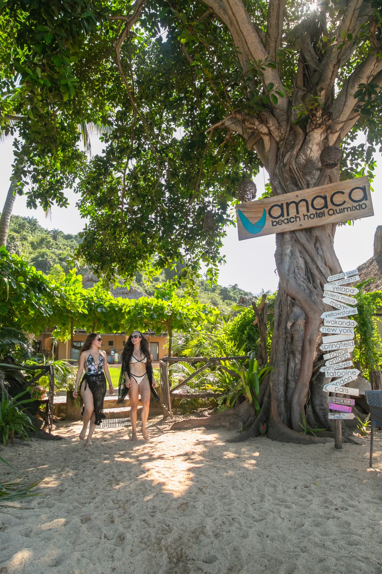 Two friends walking under the Amaca Beach Hotel Quimixto sign