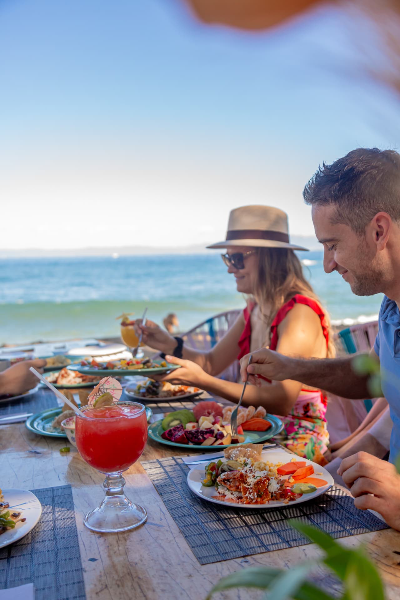 Pareja comiendo en la mesa del beach club con vista al mar