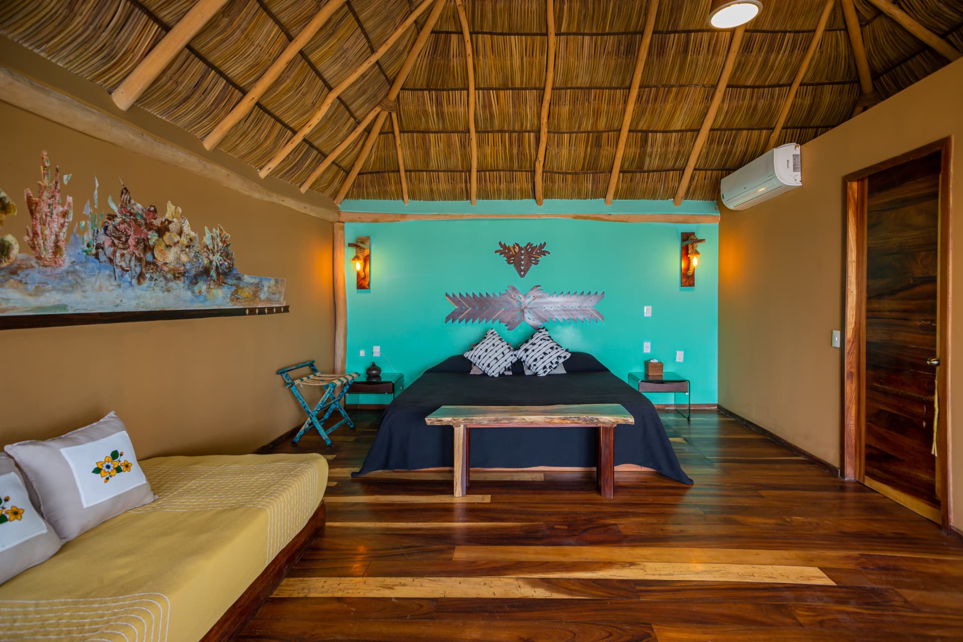 Cama King bajo el techo de palapa con piso de madera noble