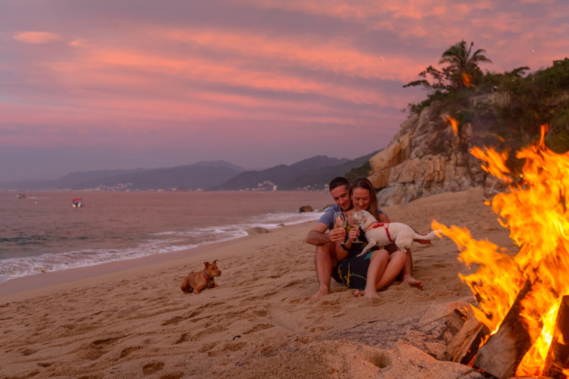 Couple toasting with wine beside the beach bonfire