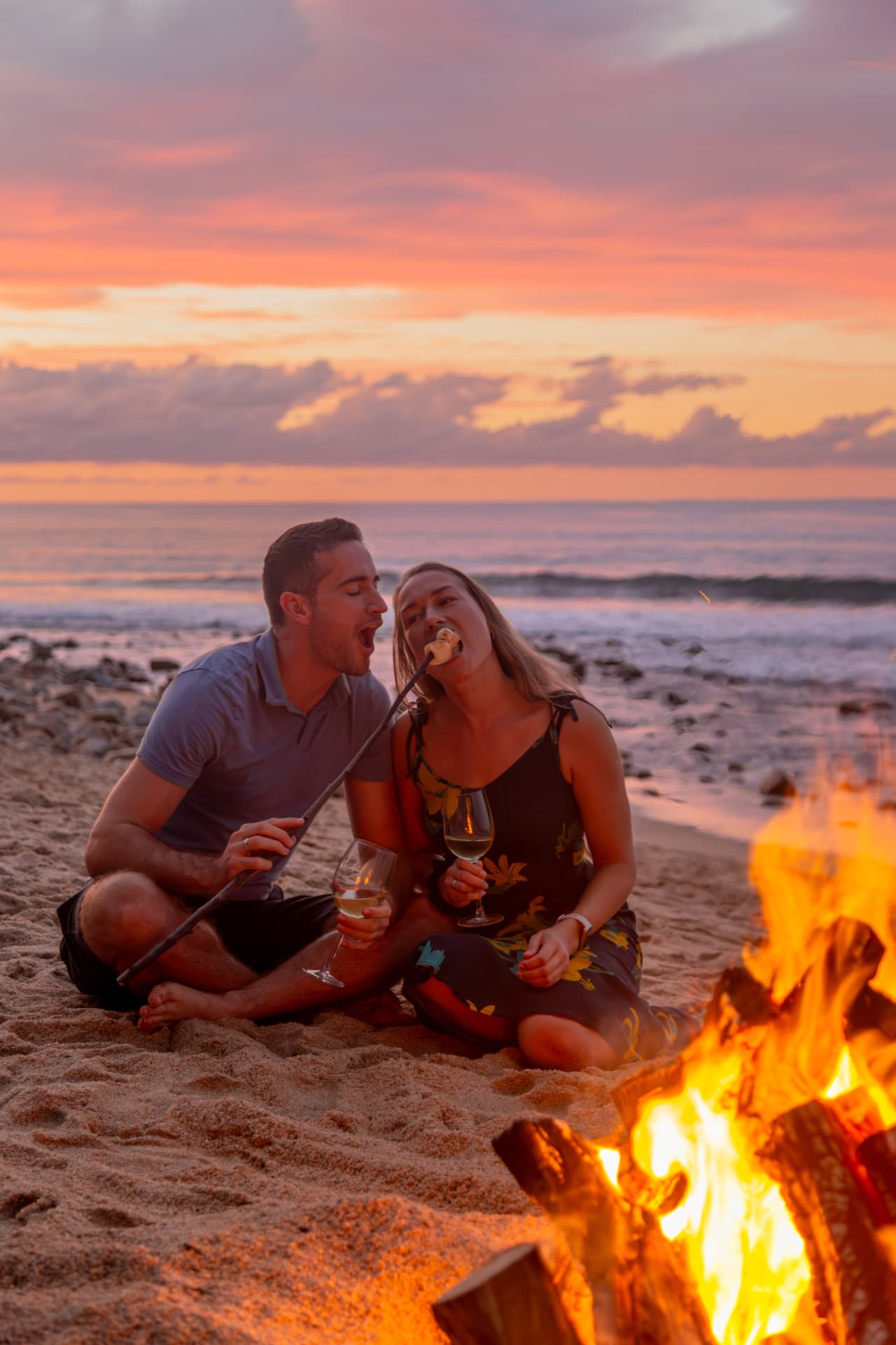 Couple sharing a roasted marshmallow by the bonfire at sunset