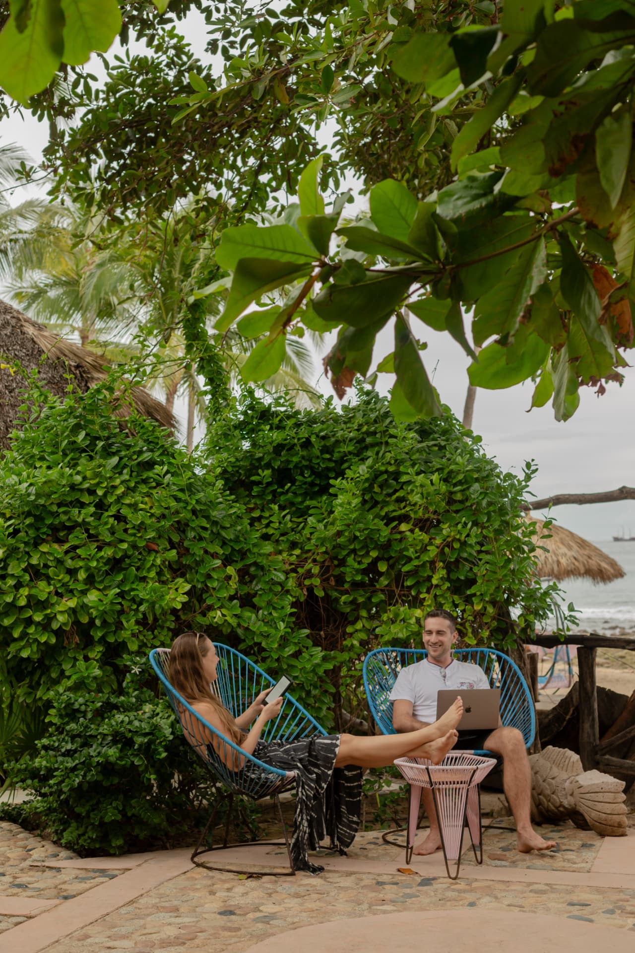 Couple reading and working under the trees with the sea behind